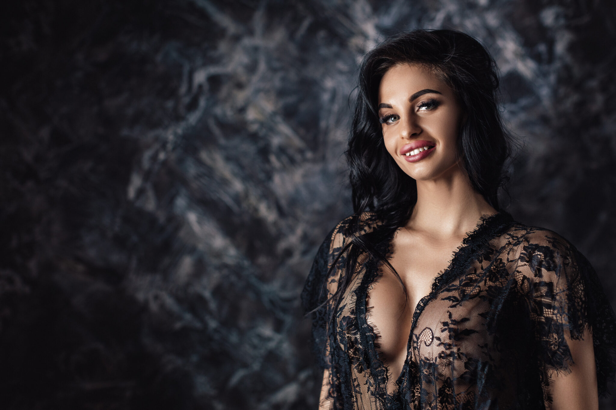 portrait of sexy beautiful smiling woman in lace black sensual lingerie with long curly hair posing in studio.