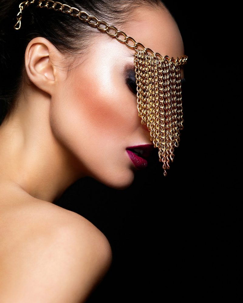 High fashion look.glamor closeup portrait of beautiful sexy Caucasian young woman model with colorful lips,bright makeup, with perfect clean skin with jewelery on eye isolated on black