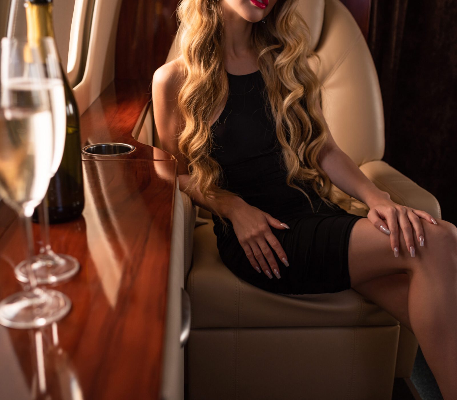cropped view of glamorous woman with champagne sitting in plane